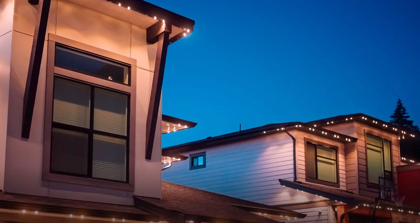 A home lit warm along its roofline after dark, the track itself invisible against the fascia.